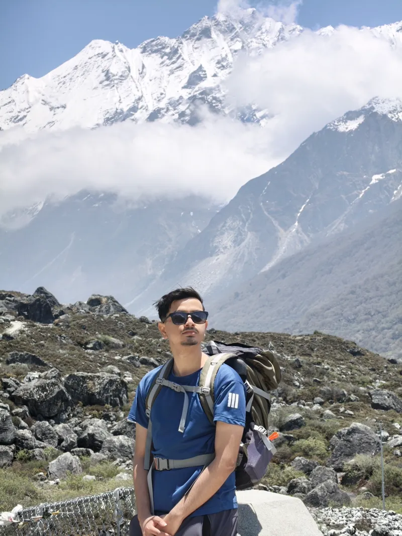 Anuj Paudel standing before the snow-capped Langtang range in Nepal
